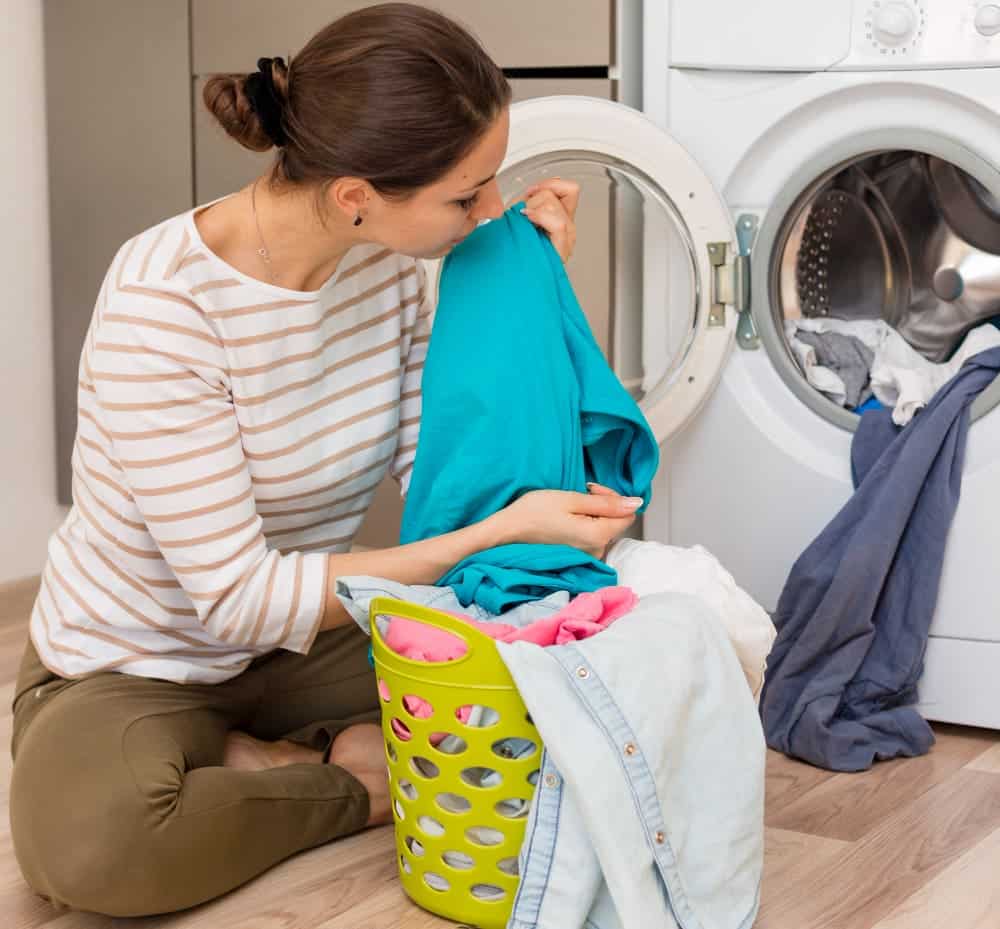 casual woman smelling clean laundry min